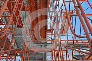 Scaffolding. Lattice mast, cables or poles in busy industrial under construction site with cranes. Steel or metal structure.