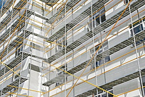 Scaffolding near a new house, building exterior, construction and repair industry, white wall and window, yellow pipe