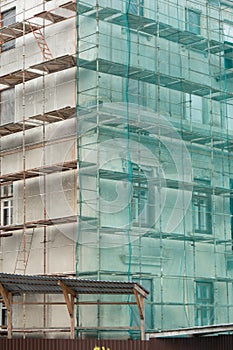 Scaffolding outside the house covered with green mesh