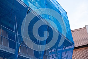 Scaffolding in a protective blue grid. building work. Home construction.Building materials and the process of repair a