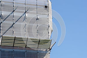 Scaffolding structure with fall protection sheet. Facade structure for building maintenance.