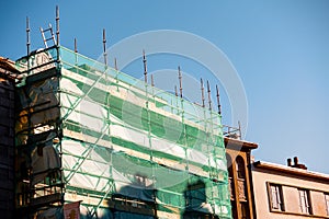 Scaffolding structure in old town. House restoration and repair. Construction industry equipment to work in public places and