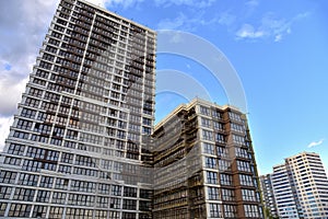 Scaffolding used in construction new building. Facade of a new modern high-rise residential building. Skyscraper on blue sky