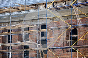 Scaffolds installed near the multi-storey brick building under constructio