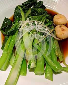 Scalding green vegetables with soy sauce in the plate photo