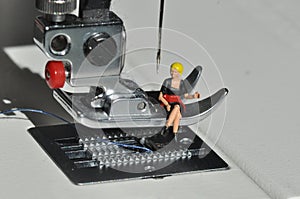 Scale H0 diorama: housewive sits relaxing on  a sewing foot of an electric sewing machine