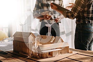 Scale model house on table with architects. Two architects making architectural model in office together. to form a new buildin