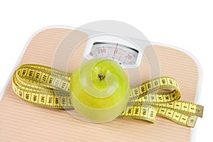 Scale, tape and apple on white