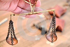Scales of bronze on a chain in a woman`s hand. Vintage scales for weighing precious metals and money