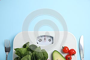 Scales, healthy food and cutlery on light blue background, flat lay. Space for text