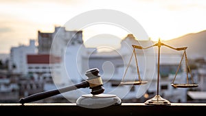 The scales of injustice and the lawyer hammer placed on the building-background table with the evening