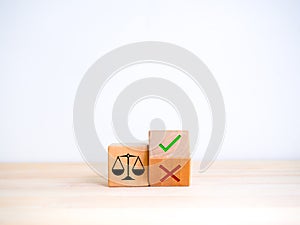 Scales of justice, icon on wood cube near green check mark and red cross symbol on flipping wooden block.