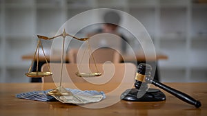 Scales of justice placed on money and lawyer hammer on the table, the background