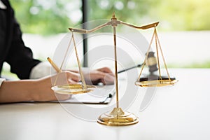 Scales of justice on white table background with female lawyers working at the law firms