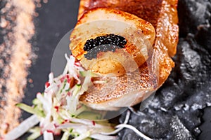 Scallops and ravioli. Seafood, pike perch fish, caviar and black dumplings in a plate on a dark table close-up. Healthy