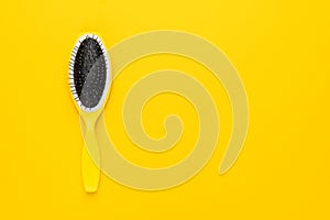 Scalp massage comb on the yellow background with copy space