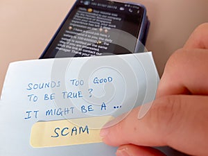 Scam alert concept. Finger pointing a note with the words Sounds Too Good To Be True It Might Be A Scam