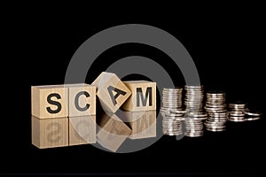 SCAM - text on wooden cubes on dark backround with coins. business concept