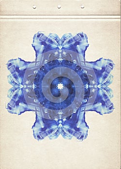 Scan of a card with blue color watercolor paint symmetric snowflake on old paper. Abstract watercolour painting on aged paper. Fin