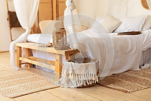Scandinavian bedroom interior decoration with comfortable bed and pillows. Cozy room with decoration and wisker basket with plaids