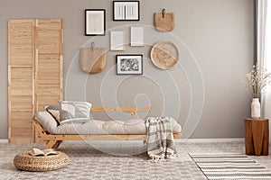 Scandinavian beige futon with patterned pillows and blanket in natural style living room interior