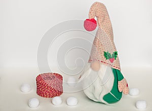 Scandinavian gnome in green clothes with a ball of thread on a white background
