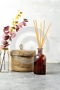 Scandinavian hygge style, home interior - aroma diffuser with wooden sticks, straw basket, dried eucalyptus branches