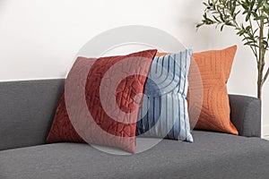 Scandinavian interior decoration of grey sofa with blue, red and orange pillow on it.