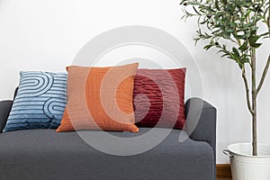 Scandinavian interior decoration of grey sofa with blue, red and orange pillow on it.