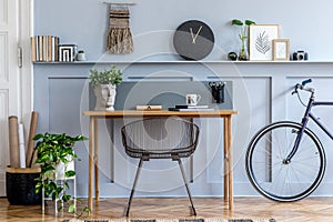 Scandinavian interior design of home office space with wooden desk, modern chair, wood paneling with shelf, plant, carpet, bicycle