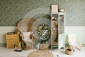 Scandinavian mint Christmas interior with decorated Christmas tree in children`s room. Wardrobe with children`s toys, wicker cha