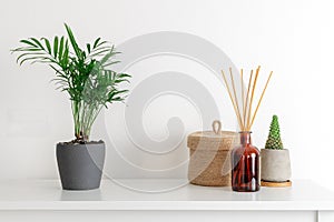 Scandinavian nordic hygge style, home interior - candle, scent aroma diffuser, small straw basket, white shelf photo