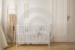 Scandinavian nursery with white wooden crib, real photo with copy space