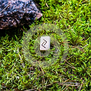 Scandinavian rune Jera, a symbol of the crop, on wet moss. The concept of predicting the future, an ancient way of divination.