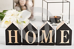 Flowers and lit candle, wooden letter Home