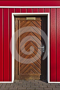 Scandinavian-style bright red and white facade with brown wooden herringbone door