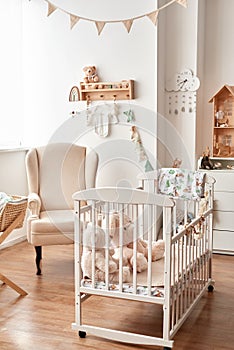 Scandinavian style white interior children's room, bedroom, nursery. Baby cot with canopy. Wooden shelves and toys