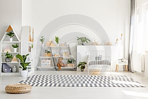 Scandinavian style, wooden furniture with plants and mountain decorations in a sunny, monochromatic child bedroom interior with wh