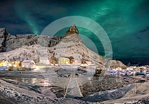 Scandinavian village with aurora borealis over snowy mountain