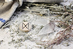 Scandinavian wooden rune Dagaz, Daeg on a rough linen cloth with amethyst crystalline, rock crystal and dried wormwood