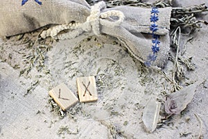 Scandinavian wooden rune Kenaz and Gebo on a rough linen cloth with amethyst crystalline, rock crystal and dried wormwood