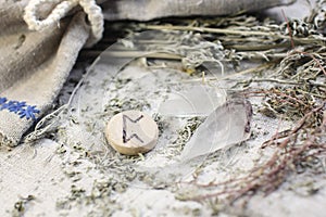 Scandinavian wooden rune PERTHRO on a rough linen cloth with amethyst crystalline, rock crystal and dried wormwood