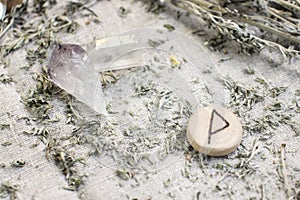 Scandinavian wooden rune Wunjo on a rough linen cloth with amethyst crystalline, rock crystal and dried wormwood