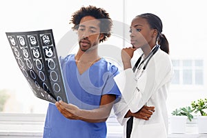 The scans will help them with a diagnosis. a female doctor and male nurse studying a CAT scan.