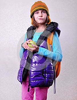 Scaptical schoolgirl with backpack and apple