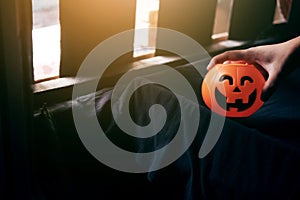 Scare hand holdung Halloween pumpkin head on black clothes in natural sunlight. Halloween holiday concept