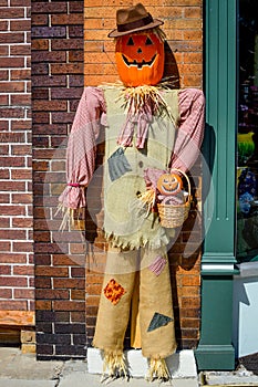 Pumpkin Scarecrow Against Building Holding Basket