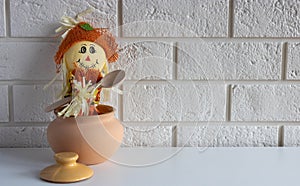 A scarecrow with a wooden spoon in a clay pot on a white background.The concept of Halloween and Thanksgiving. Place for