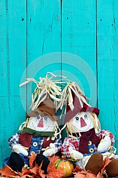 Scarecrows sitting by fence and fall decor