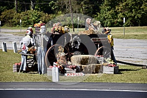 Scarecrows with wooden cart of flowers and fruit on grassed park. Cumberland County, Tennessee, USA.